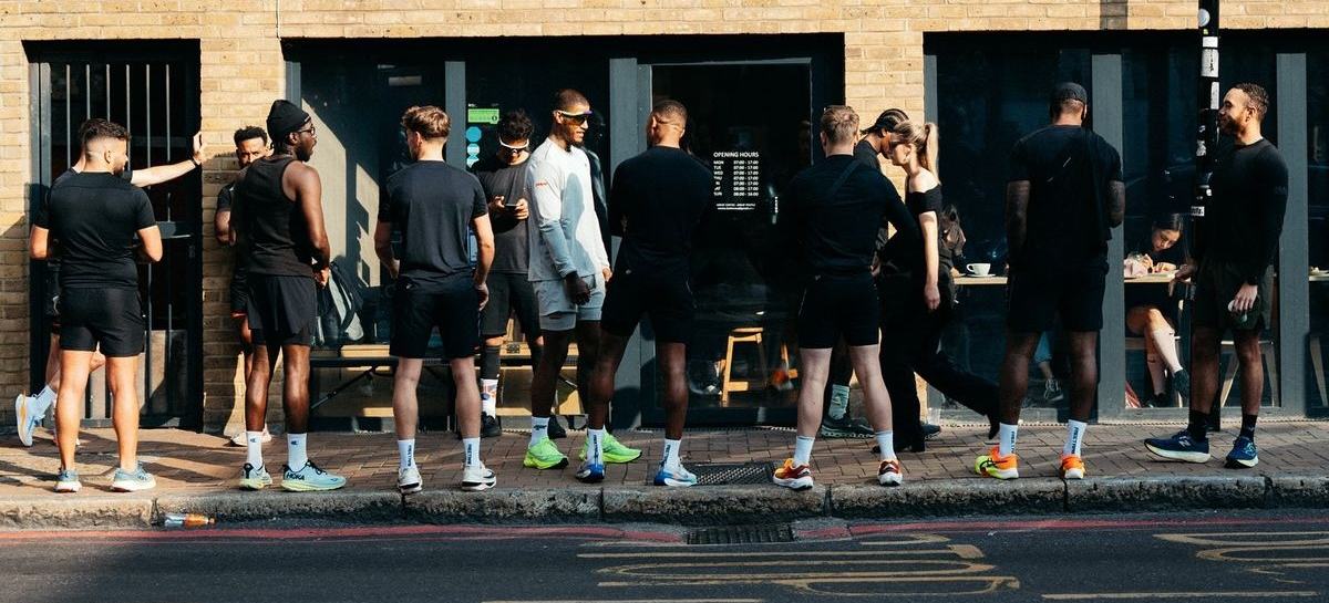 A group of people gathered on the pavement outside a coffee shop